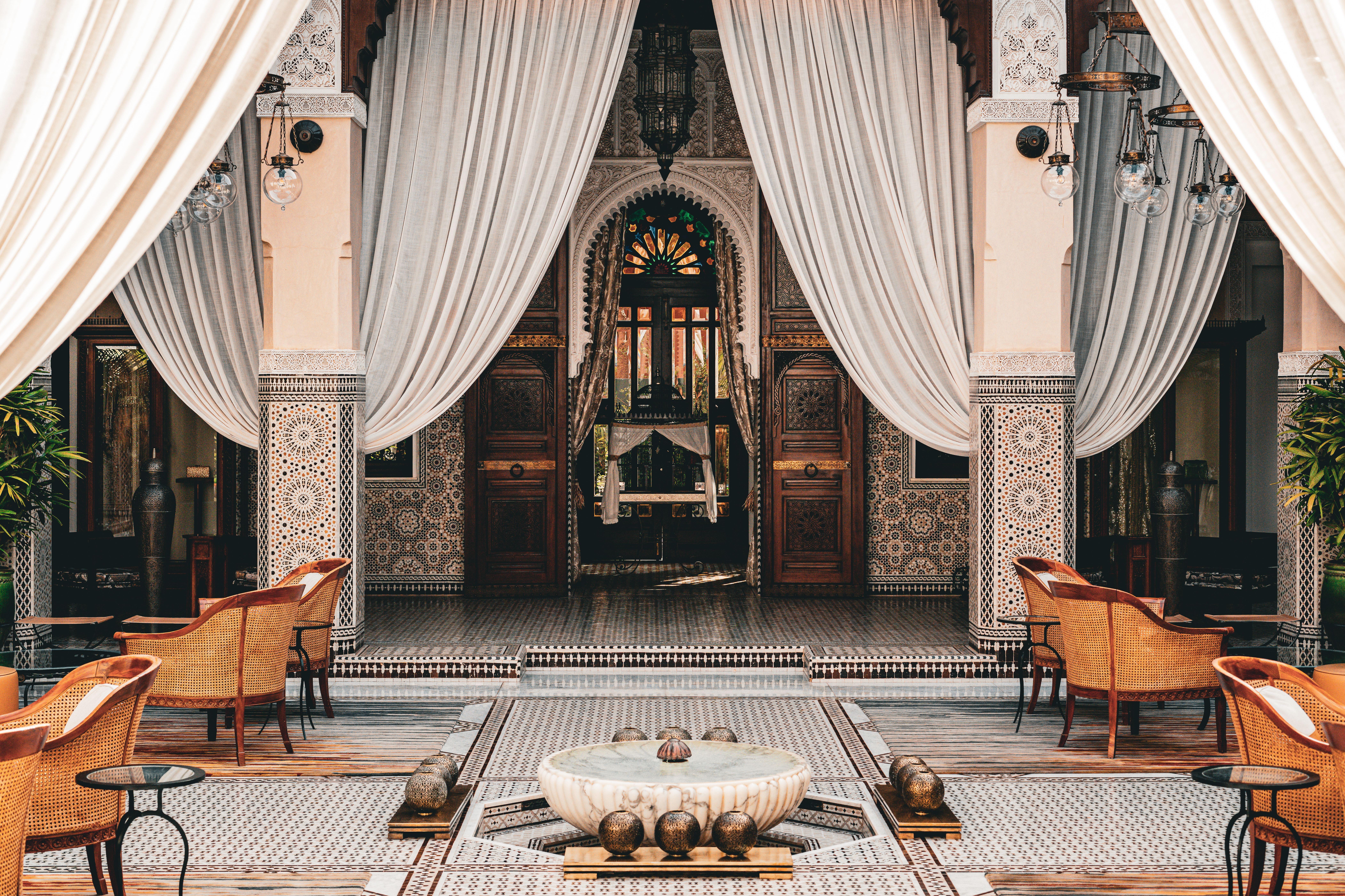 Luxury Moroccan riad courtyard with carved arches and marble fountain
